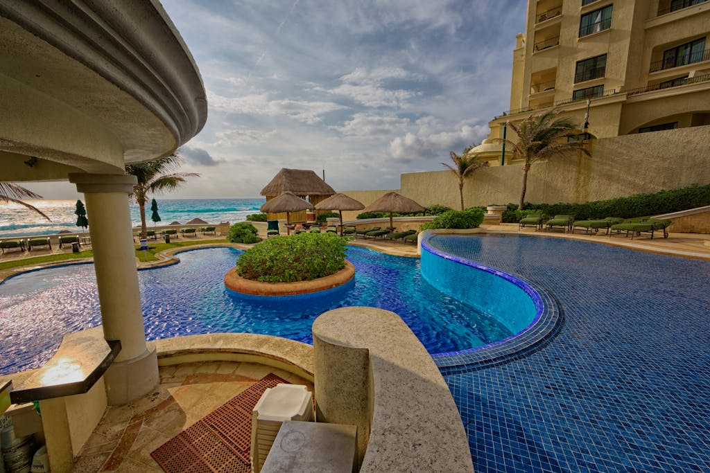 Relaxing poolside at a luxury resort in Mexico with scenic ocean views and palm trees.